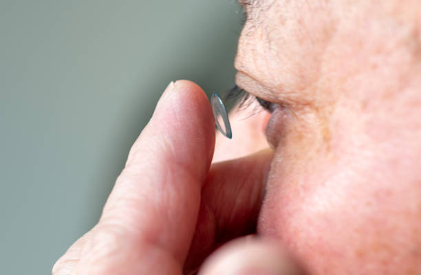 A person inserting a contact lens in the eye.