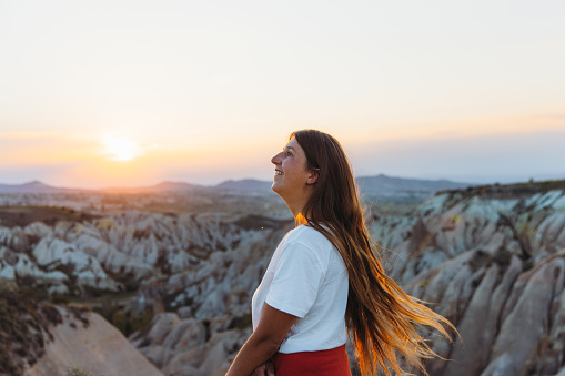 Side view of a happy female with long hair admiring the sunset with a view of the beautiful valley Göreme National park, Middle East