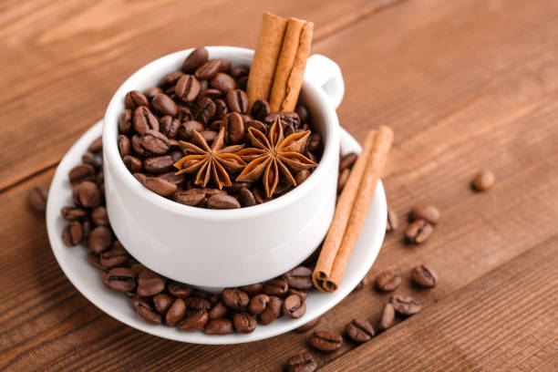Coffee beans and cinnamon on a background of burlap. Roasted coffee beans background close up. Coffee beans pile from top with copy space for text. Seasoning. Spice. Cinnamon. Badian. Coffee house.