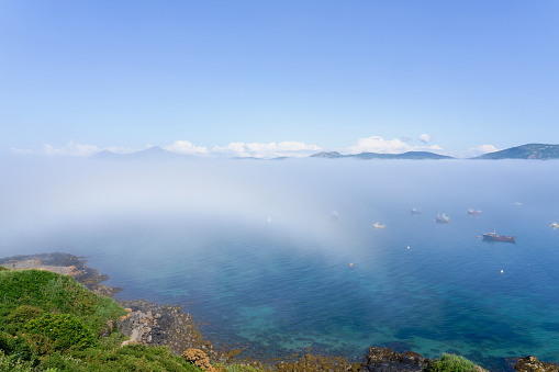 A layer of fog swirls across the clear waters of  Porthdinllaen harbour and beyond.