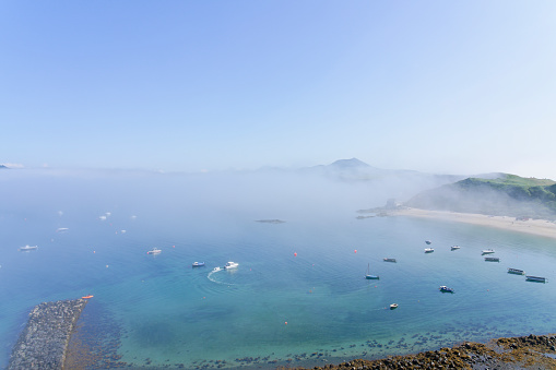 A bank of fog sits over Porthdinllaen harbour and beyond on a summer afternoon in June.