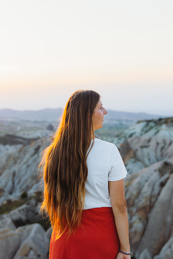 Rear view of a happy female with long hair admiring the sunset with a view of the beautiful valley Göreme National park, Middle East