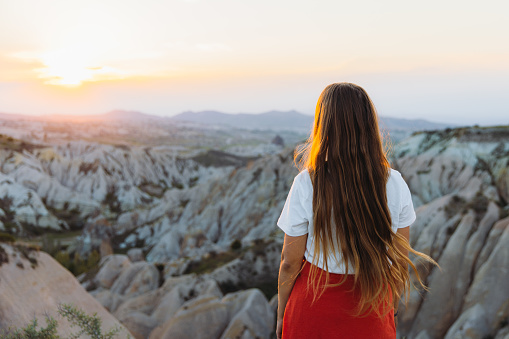 Rear view of a happy female with long hair admiring the sunset with a view of the beautiful valley Göreme National park, Middle East