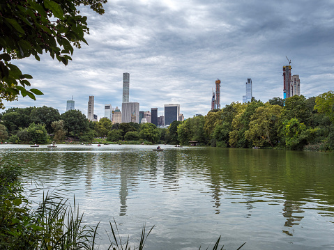 Central Park Lake and West Side skyline, New York City. People rowing on the lake.
