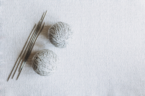 Balls of wool yarn and needles for hand knitting on a grey background. Concept for handmade. Place for text