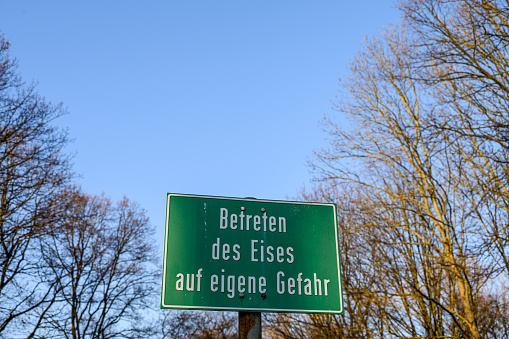 Warning sign in German 'Betreten des Eises auf eigene Gefahr' translating to \
