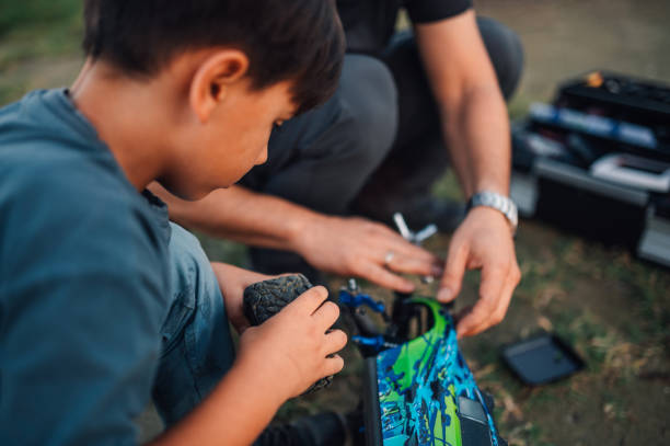 istock Boy changing a tire on a remote control car while his father is assisting him. 1937327922