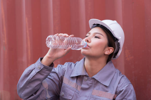 istock Female container worker drinking water in break time at commercial dock site 1937355566