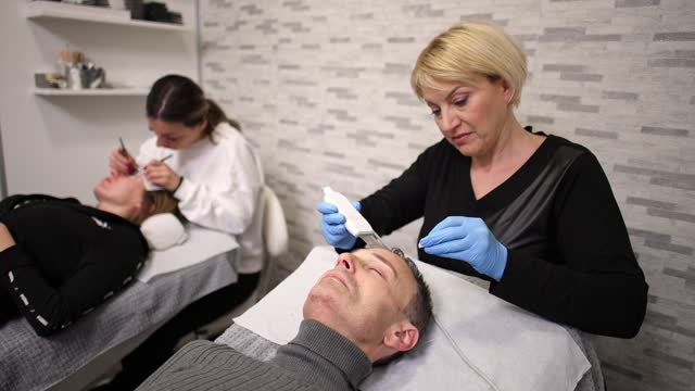 At the beauty salon, mid-adult man receiving ultra peeling facial treatment from an female Caucasian beautician