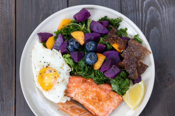 healthy salad with fried egg, salmon, kale, sweet potato and blueberries on white plate. - filet mignon bacon fillet steak - fotografias e filmes do acervo