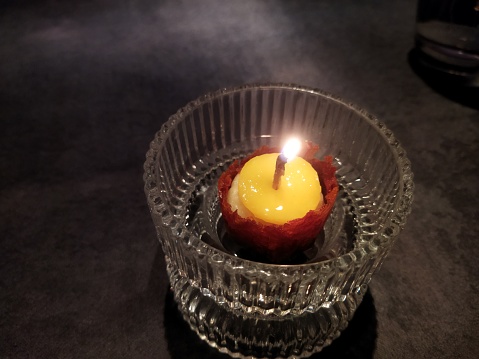 Multi-colored round cylindrical candles in a black fake fireplace.