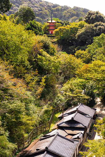 Kyoto, Japan - October 10th, 2023: Beautiful famous three story Koyasu Pagoda on the Kiyomizu-dera temple grounds surrounded by green forest in autumn and classic Japanese architecture rooftops.