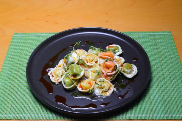 Italian tortellini pasta in cream sauce.with spinach. White wooden background. Top view