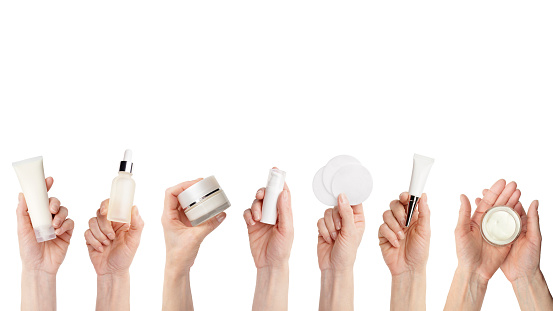 Female caucasian hands hold beauty skin care products over white background with copy-space