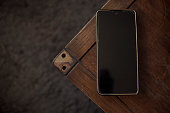 top view of cell phone with screen off on wooden table and copy space