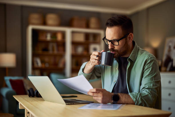 istock A male freelancer drinking coffee while analyzing his work on a laptop with a document in his hand. 1937423895