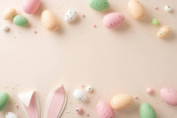 istock A festive Easter scene unfolds in this top-view snapshot. Vibrant eggs, endearing bunny ears and sprinkles decorate a pastel beige surface with an open area for your text or advertisement 1937429224