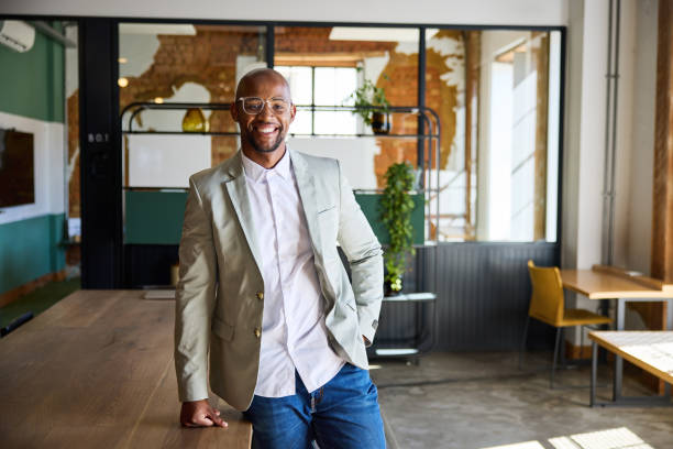 Smiling young businessman leaning on a table in an office