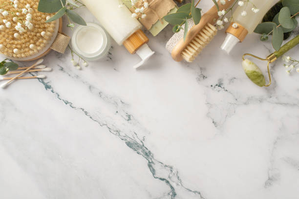 istock Natural self-care ensemble. Top view shot featuring gua sha roller, cream, anti-cellulite brush, handmade soap, pumice, cotton buds, eucalyptus, flowers on marble background with empty space for text 1937429783