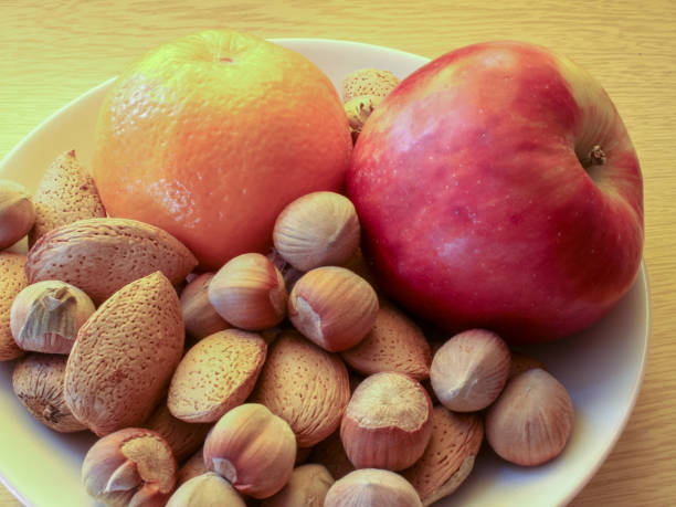Fruits and nuts in the plate placed on a table, closeup of photo
