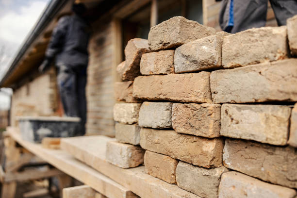 istock Selective focus on a pile of rustic bricks on a construction site with workers building a house. 1937459405