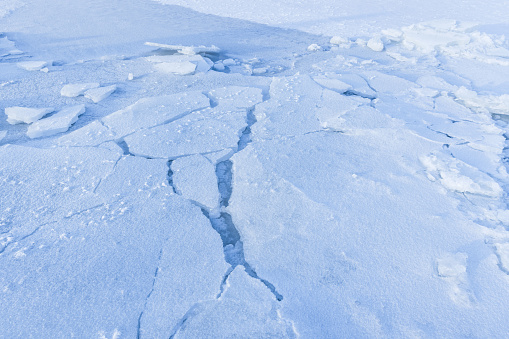 Ice hummocks covered with snow. Broken ice fragments lay on the coast of frozen Baltic Sea on a winter day