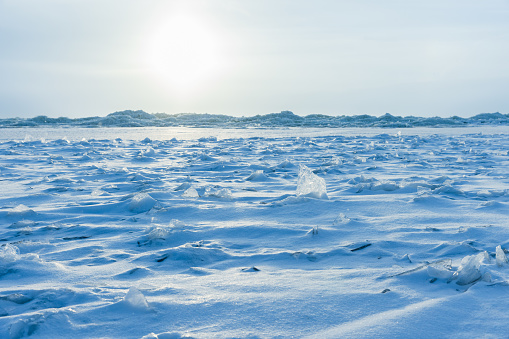 Empty winter landscape with frozen Baltic sea under blue sky on a sunny day. Sharp ice fragments are covered with snow