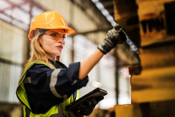 istock woman worker carpenter wearing safety uniform and hard hat working and checking the quality of wooden products at workshop manufacturing. man and woman workers wood in dark warehouse industry. 1937469901