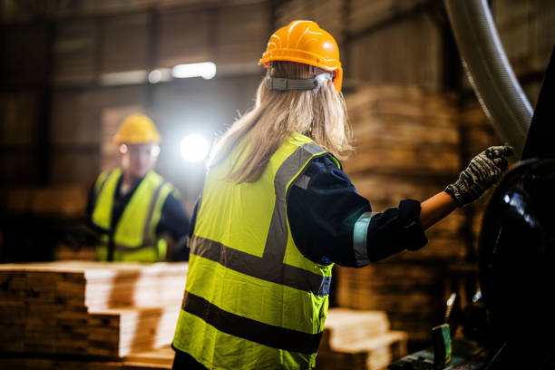 istock Team worker carpenter wearing safety uniform and hard hat working and checking the quality of wooden products at workshop manufacturing. man and woman workers wood in dark warehouse industry. 1937471500