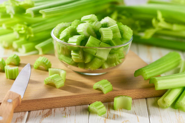 whole and chopped organic celery on a wooden table. stock photo