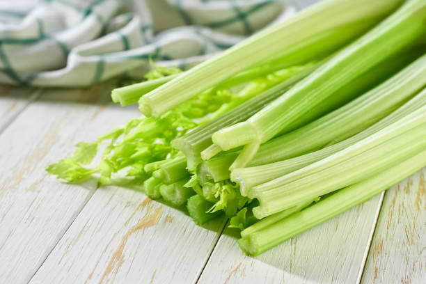 fresh green celery stalks on a white wooden table. stock photo