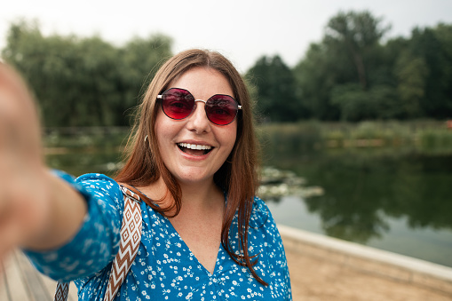 Portrait of beautiful cheerful young woman having a good time at the beach on a lovely day, taking a selfie in Europe at summer day. High quality photo