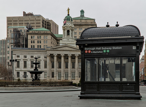 Brooklyn, NY - Jan 15, 2023: View of Borough Hall train station entrance (2,3,4,5 subway trains) with courthouse and fountain on a cloudy overcast day in downtown Brooklyn, New York City.