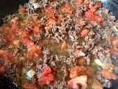 Ground beef, tomato and onion slices cooking