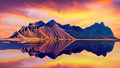 Exciting beautiful landscape with most breathtaking mountains Vestrahorn on the Stokksnes peninsula in the mirror of the lake at sunset. Exotic countries. (Meditation, antistress - concept).
