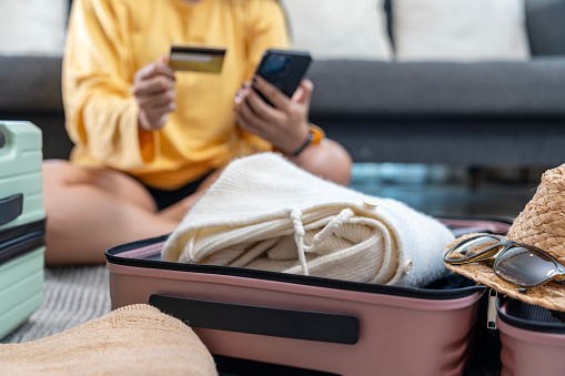A travel bag ready for a trip, and a background image of a woman paying for accommodation with a credit card