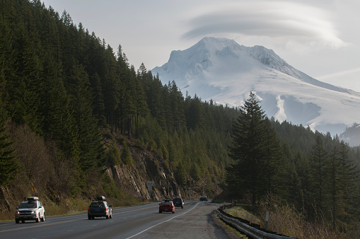 Cars driving on a mist-covered, snow-capped mountain highway in Mount Hood, Oregon