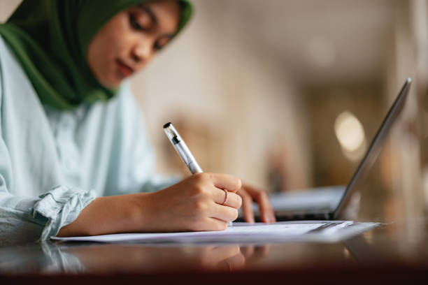 istock Anonymous Young Female Wearing Hijab Writing and Using Laptop Computer for Studying 1937529043