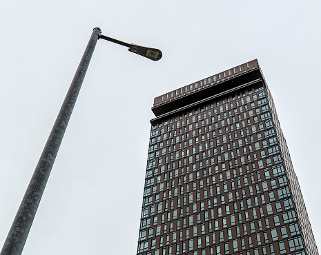 street light against gray sky with tall residential and commercial building in the background (lamp, streetlight, high rise, tower)