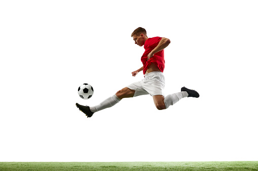 Aerial Symphony of Soccer. Athleticism. Portrait of soccer maestro orchestrates airborne pass, the ball dancing through air against white background with green field. Concept of sport games, match.