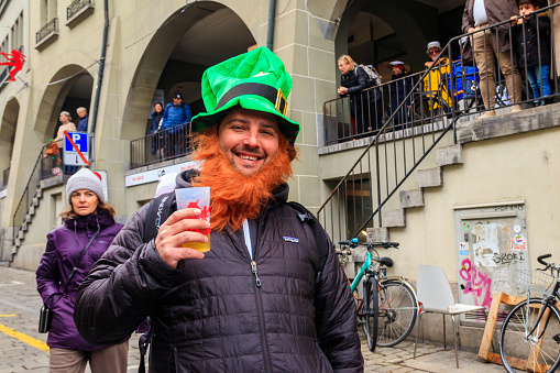 Bern, Switzerland - February 25, 2023: Portrait of man wearing green leprechaun hat during carnival in Bern, Switzerland