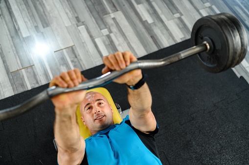 Confident man training muscles with a barbell in the gym