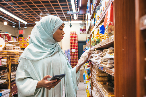 Black woman wearing abaya in a grocery store in New York, she walks thought production aisle