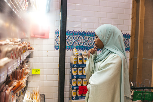 Black woman wearing abaya in a grocery store in New York, she walks thought production aisle