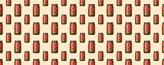 Horizontal banner of seamless pattern of glass jars big and small with canned tomatoes is isolated on yellow background.
