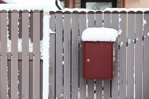 A snow-covered mailbox by a wooden fence, a snowy day.