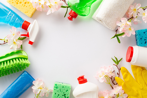 Refresh your surroundings with cleaning gear. Overhead shot of scrub brush, gloves, spray, dish soap, gels, garbage bags, flowers on a clean white backdrop. Perfect for text or promotional use