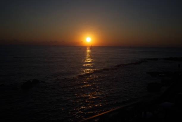 Small boat sailing past the rising sun