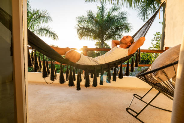 istock Man relaxing in an hammock on her balcony at sunrise 1937635142