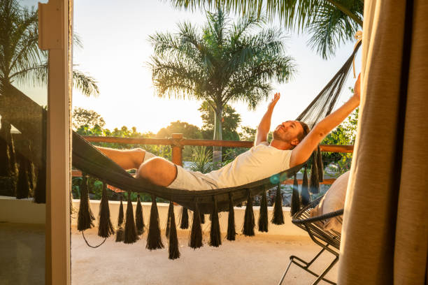 istock Man relaxing in an hammock on her balcony at sunrise 1937636716